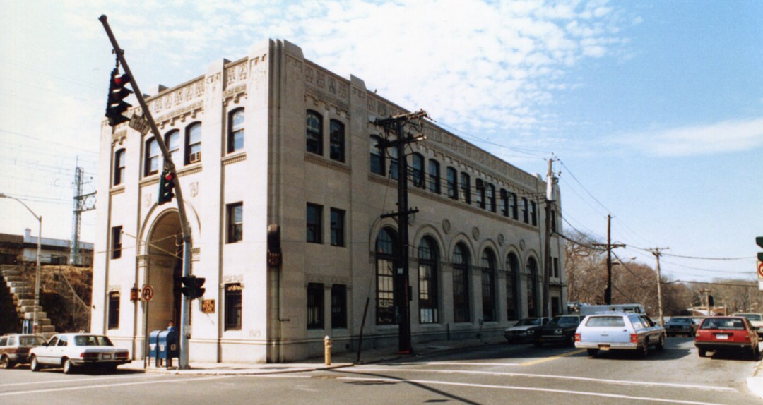 Historical view of 3-story limestone building with 1980s vehicles on roads