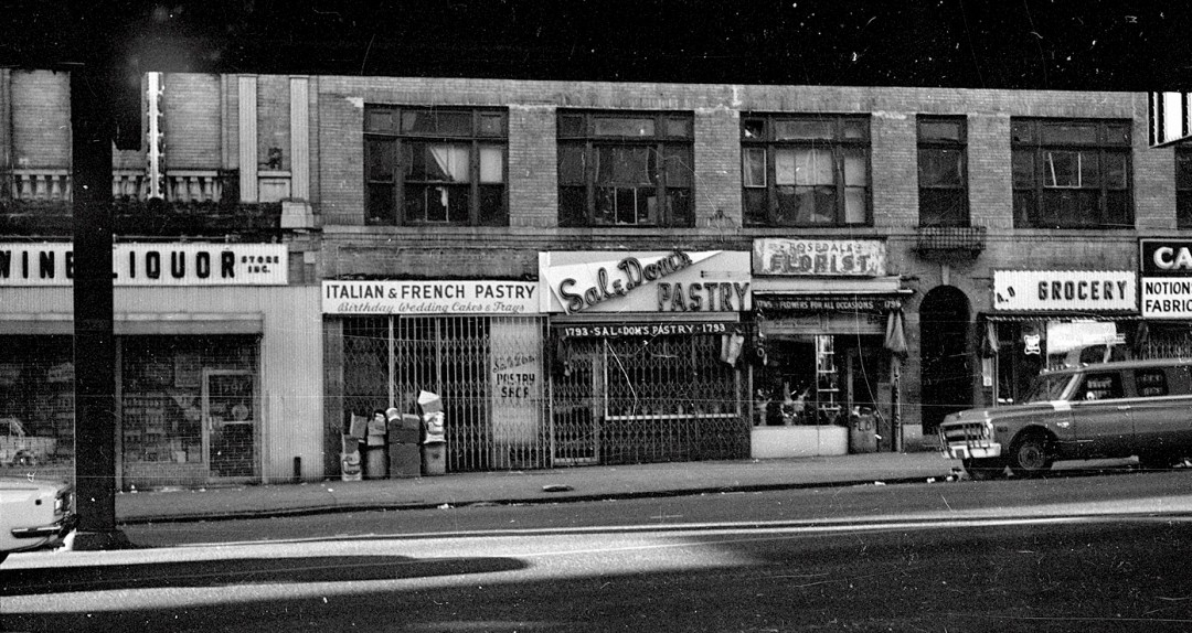Historical view of brick retail storefronts under elevated train line